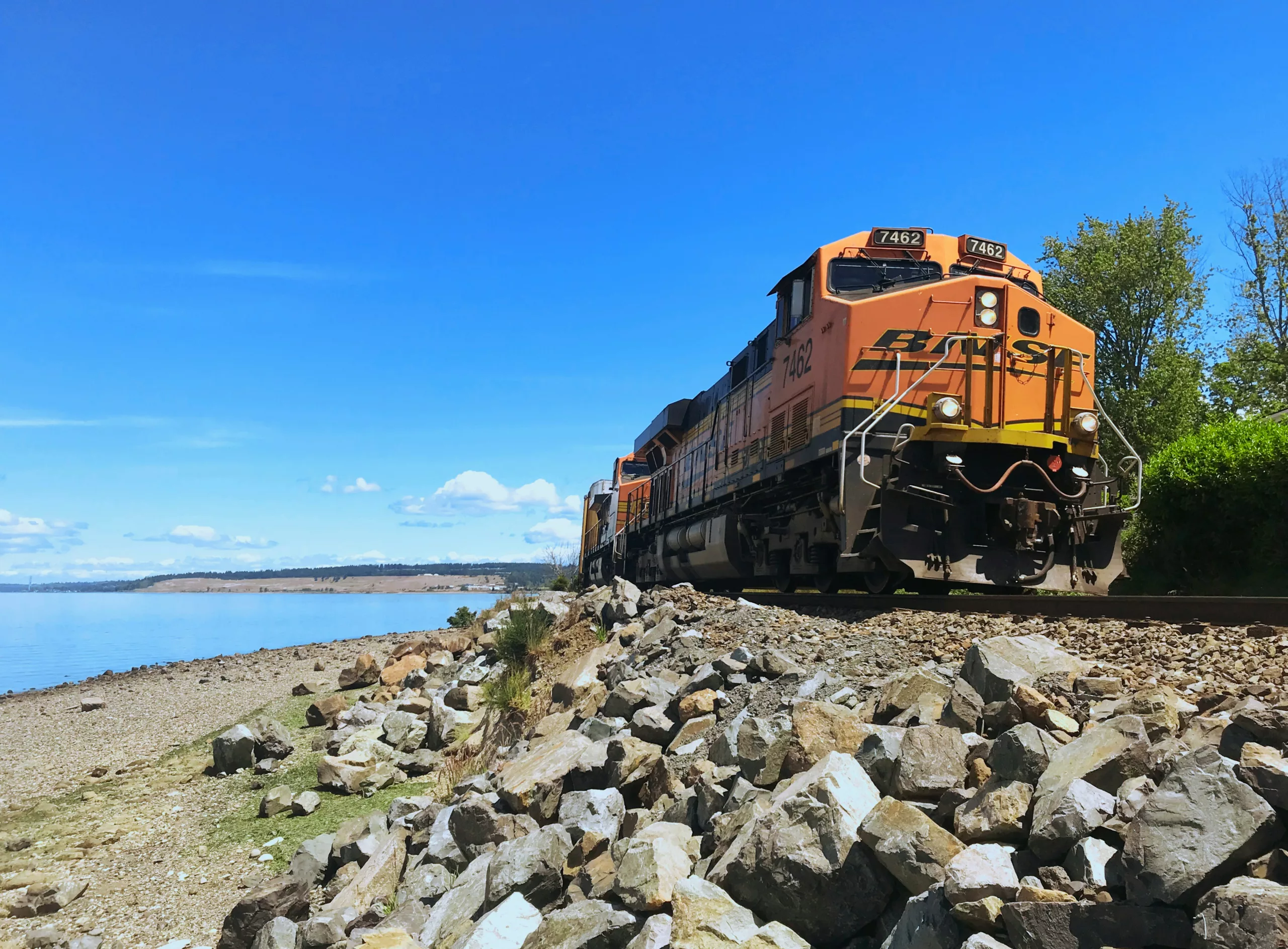 Orange train moving along a rocky beach Steilacoom, WA