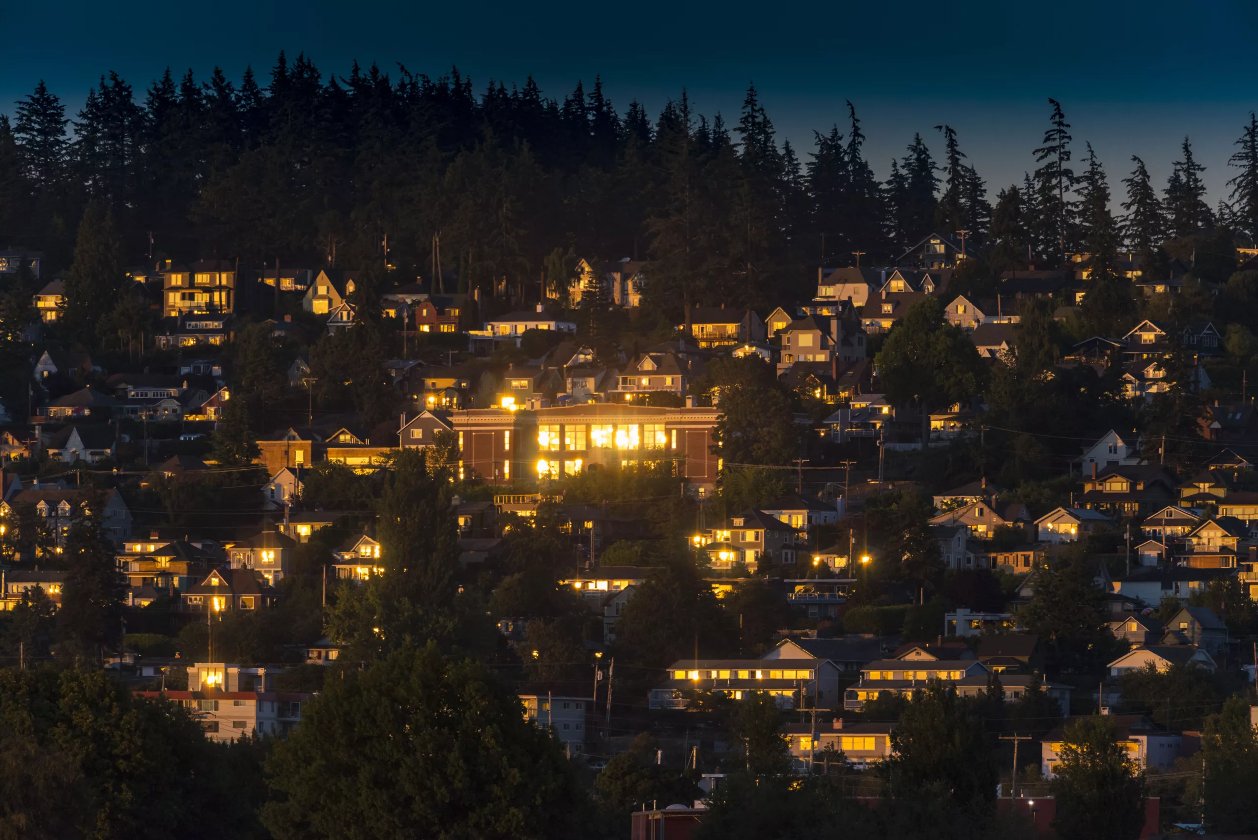 Sunset view residential neighborhood homes lit evening forest background South Hill, WA
